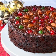 a chocolate cake topped with nuts and cherries on top of a white platter