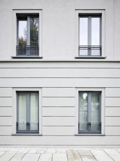 two windows on the side of a white building