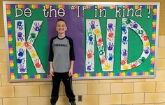 a young boy standing in front of a sign that says be the i'm kind