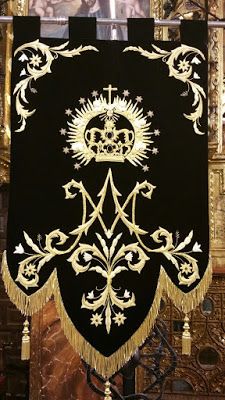 an ornate black and gold banner hanging from the ceiling in front of a wall with pictures on it