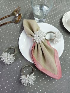 napkins and rings are sitting on a plate with silverware next to the napkin