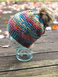 a multicolored knitted hat with a pom - pom on top