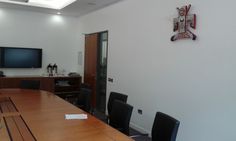 a large wooden table with black chairs and a flat screen tv mounted on the wall