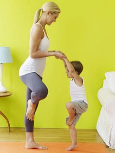 a woman and child doing yoga in front of a yellow wall