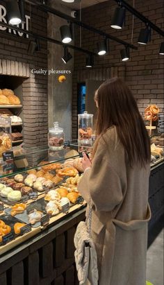 a woman standing in front of a display case filled with pastries