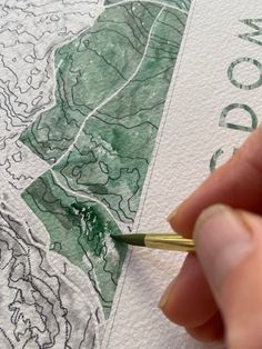 a hand holding a pencil over a map with the word wood on it and trees in the background