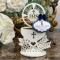 a white card with a cross on it and flowers in front of the card holder