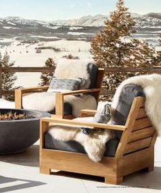 two wooden chairs sitting on top of a patio next to a fire pit in the snow