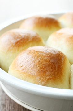 several rolls in a white bowl on a table