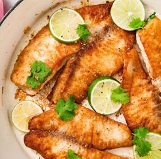 fish with limes and cilantro on a white plate