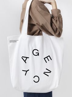 a woman holding a white bag with black letters on it