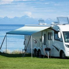 an rv parked next to the ocean under a tent