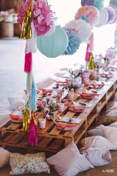 the table is set up with paper flowers and tissue pom poms on it