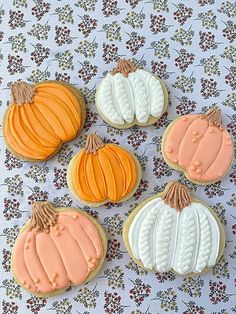 four decorated pumpkin cookies sitting on top of a table