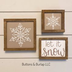 three framed snowflakes on the wall with let it snow written in white ink