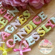 decorated cookies in the shape of letters are sitting on a table next to pink flowers