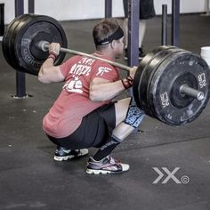 a man squats down while lifting a barbell