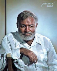 an old man with a white beard sitting in a chair and looking at the camera