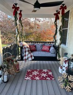 a porch decorated for christmas with red and white decorations on the front porch, couches and rugs