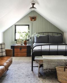 a bedroom with a bed, couch and window in the atticed room that has wood paneling on the walls