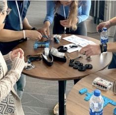 four people sitting around a table with cell phones and water bottles on top of it