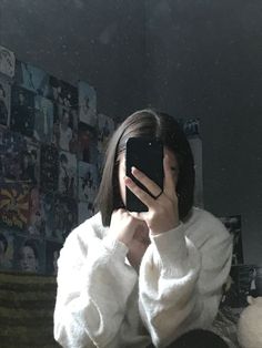 a woman taking a selfie in front of a mirror while wearing a white sweater