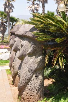 some statues are lined up on the side of a path in front of palm trees