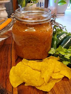 tortilla chips and salsa in a jar on a cutting board with lettuce