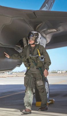 a man in an air force uniform standing next to a fighter jet