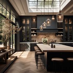 an open kitchen with lots of counter space and lights hanging from the ceiling above it