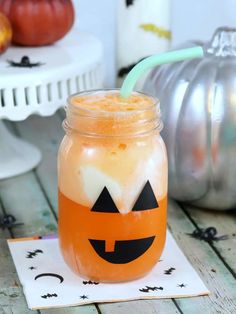 a mason jar filled with orange liquid and topped with a jack - o'- lantern face