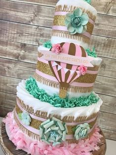 a three tiered cake with pink, green and gold decorations