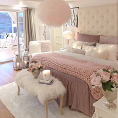 a bedroom decorated in pink and white with flowers on the bed, lights hanging from the ceiling