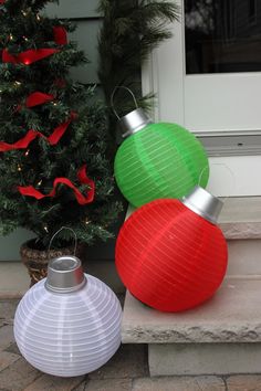 two red and green lanterns sitting next to a christmas tree