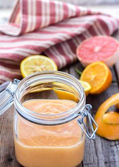 a jar filled with liquid sitting on top of a wooden table next to sliced fruit