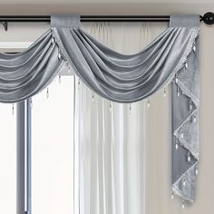 a curtain with beaded trim hanging on a window sill in front of a large window