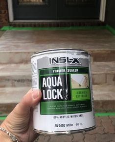 a person holding a can of aqua lock paint