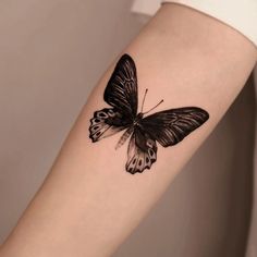 a black and white butterfly tattoo on the arm