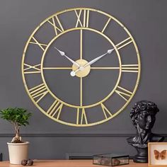 a large gold clock sitting on top of a table next to a potted plant