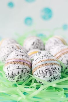 four decorated eggs with musical notes on them are sitting in the grass and have green streamers around them