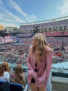 a woman standing in front of a crowd at a stadium with her back to the camera