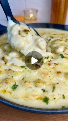 a spoon full of cheese and sauce with parsley on the top in a blue bowl