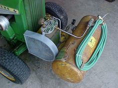 a lawn mower sitting on the ground with a hose attached to it's back end