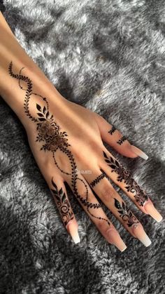 a woman's hand with henna tattoos on it