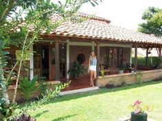 a woman standing in front of a house with an open patio and covered porch area