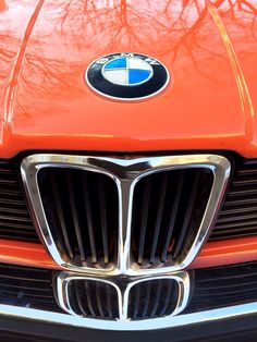 the front grille of an orange car with a bmw emblem on it's grill