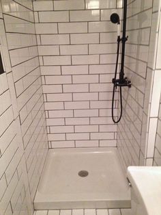 a white tiled bathroom with a shower head