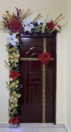 a door decorated with red and white flowers next to a gold ribbon tied around it