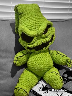 a green crocheted stuffed animal sitting on top of a couch