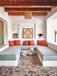 a white dog laying on top of a stone floor next to a living room filled with furniture